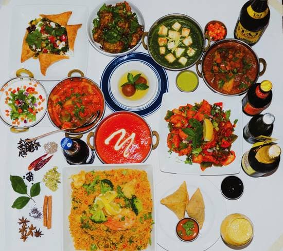 A full spread of Kathmandu Kitchen dishes — biryani, curries, naan, and drinks