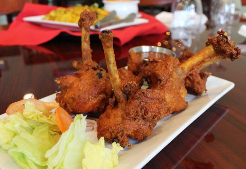 Chicken lollipops plated on a long white dish with garnish