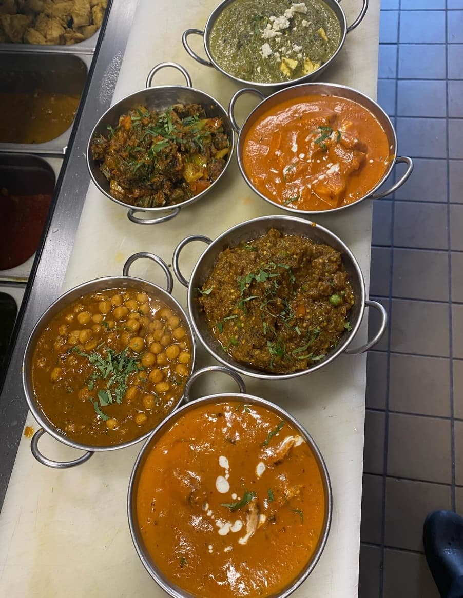 Six bowls of house curries in steel karahi, fresh from the kitchen